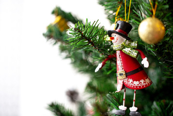 A Close up view of a Snowman figure hanging on a Christmas Tree and other ornaments