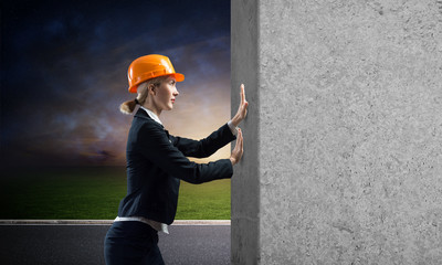 Beautiful woman architect pushing concrete wall