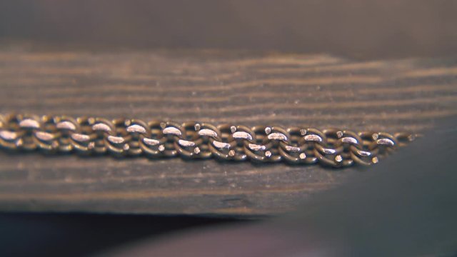 CU: professional goldsmith grinds beautiful gold chain with rasp on wooden part in jewelry workshop extreme close view