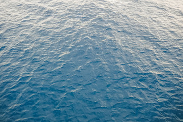 background texture of a calm deep blue ocean with ripples on the surface of the seawater, full frame