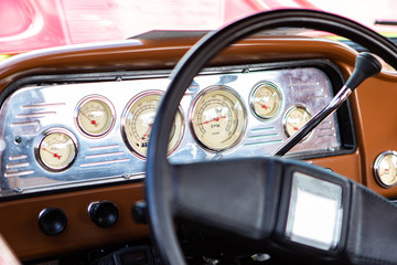 classic antique car black steering wheel and brown Dashboard close up, simple old style cars interior, Speed Counter, tachometer and other Counters