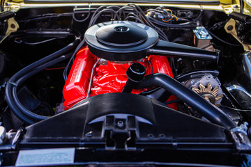 car under hood close up, view of a red engine with big black round air intake filter, tubes, wires, pipes, mechanical and electrical other parts
