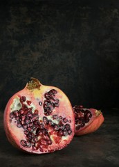 Low light image of pomegranate fruit on a dark rustic background with copy space for your text