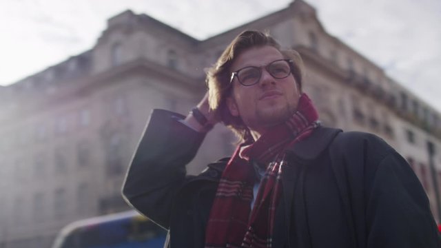 Camera circles a man in the city who looks lost and confused, in slow motion