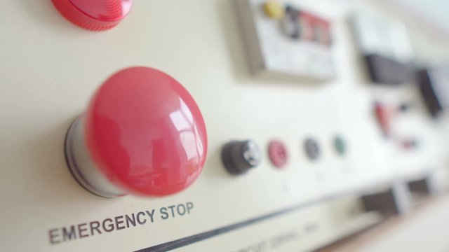 Close up selective focus on red emergency button on electric generator interface in factory central control room, safety concept
