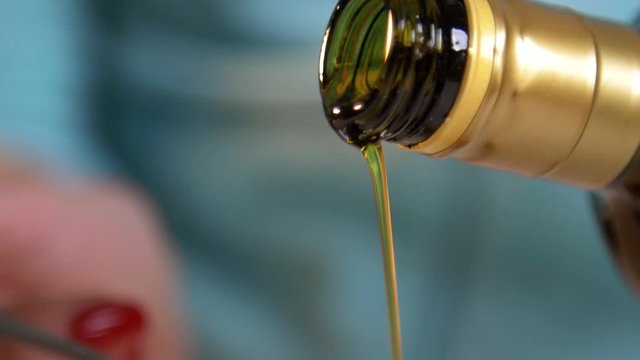 Female hands pouring olive oil from the bottle into tablespoon