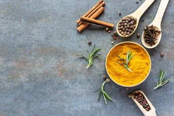 Fresh organic aromatic spices on stone rustic background with copy space for your design. Turmeric, peppercorn, allspice, anise, rosemary and cinnamon on grunge background top view.