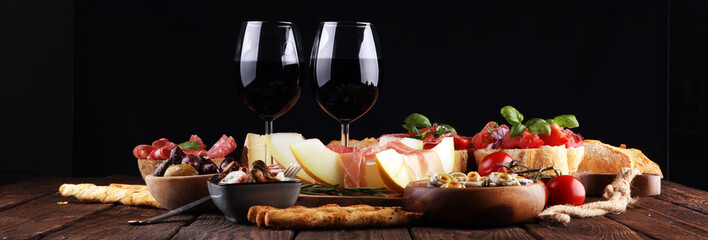 Italian antipasti wine snacks set. Cheese variety, Mediterranean olives, seafood salad, Prosciutto di Parma, tomatoes, anchovy and wine in glasses