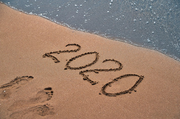 Symbols 2020 written on sand. New Year concept.