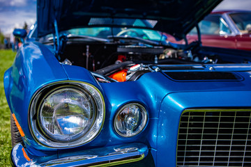 selective focus on an old vintage American muscle blue car half front, left side, with open hood,...