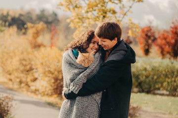 Young couple with a red cat on a background of an autumn park.