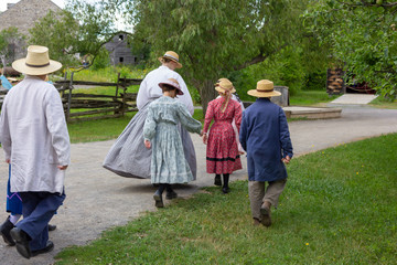 Naklejka na ściany i meble children and teacher in vintage farm clothes outdoors during the summer in North America