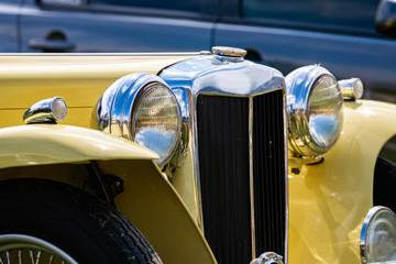 Old Classic antique car front details with cream white color and chrome body parts and big Headlamp lights and small lamps