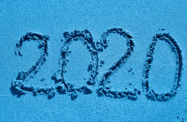 Symbols 2020 written on sand. New Year concept.