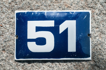 Weathered grunge square metal enameled plate of number of street address with number 51 closeup