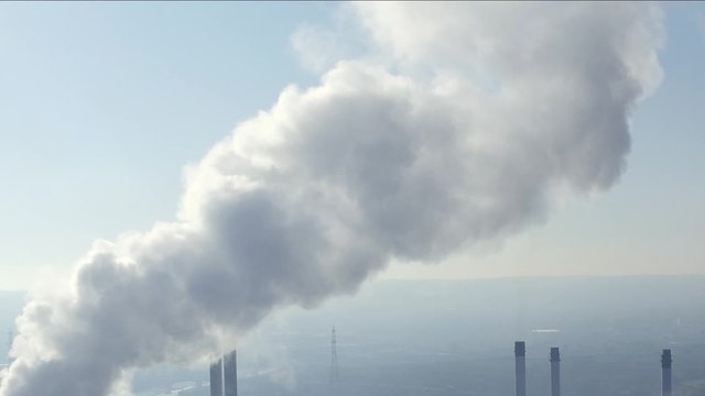 Steam billowing from a power station. Conceptual pollution shot with industrial chimneys and stacks.