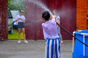 teenagers in the summer play with water and doused each other with the hose