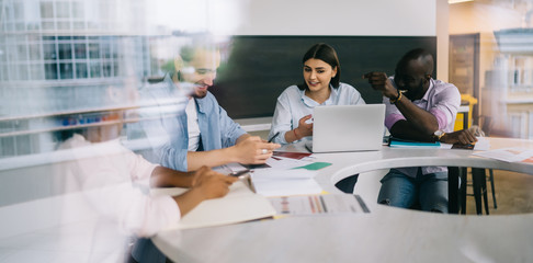 Company team working on solution using gadgets at meeting in office