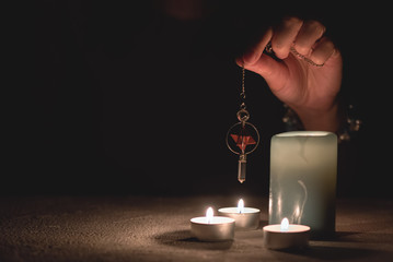 Fortune teller holding in hands a magic pendulum close up.