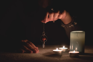 Fortune teller holding in hands a magic pendulum close up.