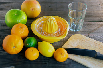 Orangen, Pampelmusen, Limetten und Zitrone mit Saftpresse Glas auf einem Hintergrund aus Holz.