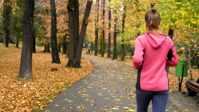 athletic young girl running in autumn Park after rain. rear view