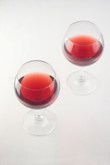  two glasses with red wine on an old wooden white countertop