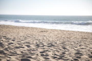 Fototapeta na wymiar Sandy beach with an ocean shoreline in the blurry background