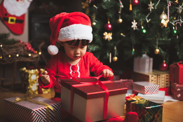 toddler girl getting christmas gift in front of christmas tree