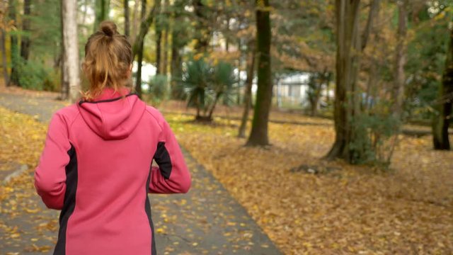 athletic young girl running in autumn Park after rain. rear view
