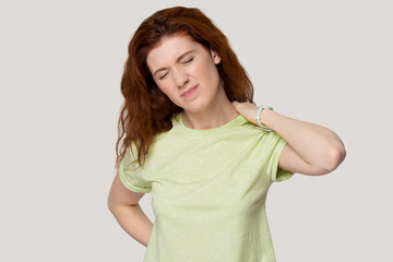 Obraz premium Studio portrait young red-haired woman suffering from strong back pain.