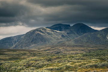 Fototapeta premium Autumn in Rondane National Park, mountain range and dark, cloudy sky, Norway.