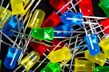 Assortment of yellow, red, green and blue LED diodes in a black table.