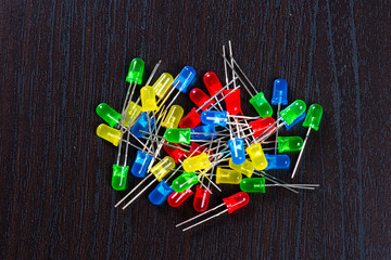 Assortment of yellow, red, green and blue LED diodes in a black table.