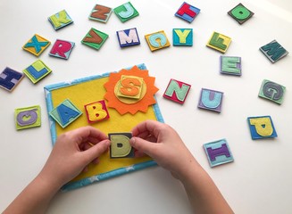 Learning the alphabet with a child. Hands hold letters. Learn by playing.