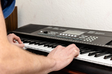 hands of a pianist man playing a synthesizer in a bright home studio