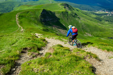 Enduro Cyclist in bright sportswear is riding down the hill.