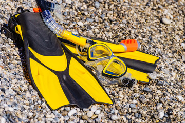 Flippers and snorkeling tube on sea shore