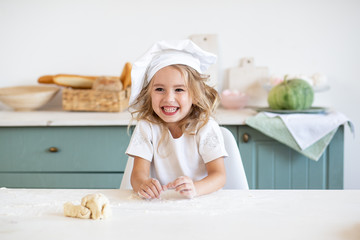 smiling girl in chef toque at kitchen at home