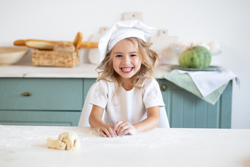 Little girl in chef toque at kitchen at home