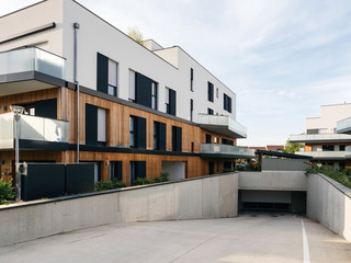 Modern townhouses in a residential area with multiple new apartments buildings surrounded by green outdoor facilities like underground parking entrance in central calm neighborhood