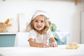 girl in a chefs toque sitting at a kitchen counter