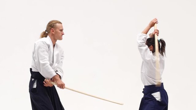 Man and woman practicing aikido using bokken. Isolated on white. Close up. Slow motion.