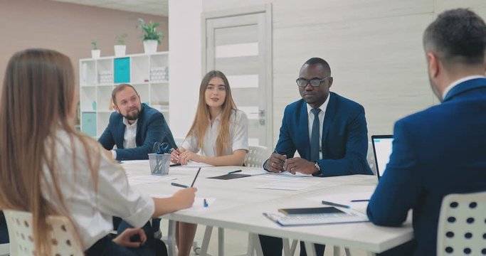 International team of young businessmen solves the financial issues of the company. Dark-skinned businessman at a meeting of directors at a table in a conference room.