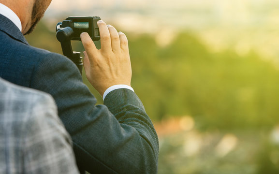 Paris, France, Jul 14, 2018: Modern Technology In Use By Businessman Wearing Business Suit Setting And Using Action Camera On A Stabilizer Monopod Gimbal