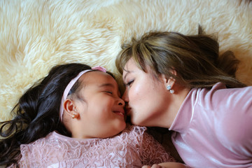Beautiful young mom and daughter dressed up for Christmas showing affection