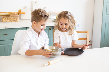 Obraz na płótnie Canvas cute children cook pancakes in the kitchen at home