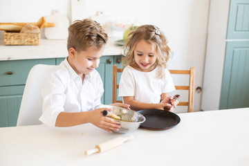 Obraz na płótnie Canvas little children cook pancakes in the kitchen at home
