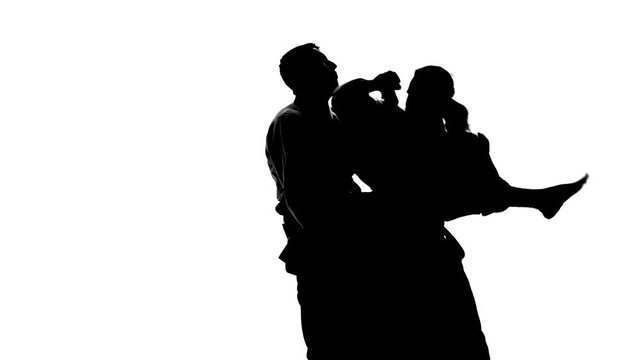 Black silhuettes of two males in keikogi or kimono demonstrating aikido techniques. Isolated, white. Slow motion. Close up.