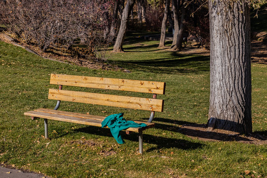 Abandoned or forgotten green fleece jacket on a park bench.